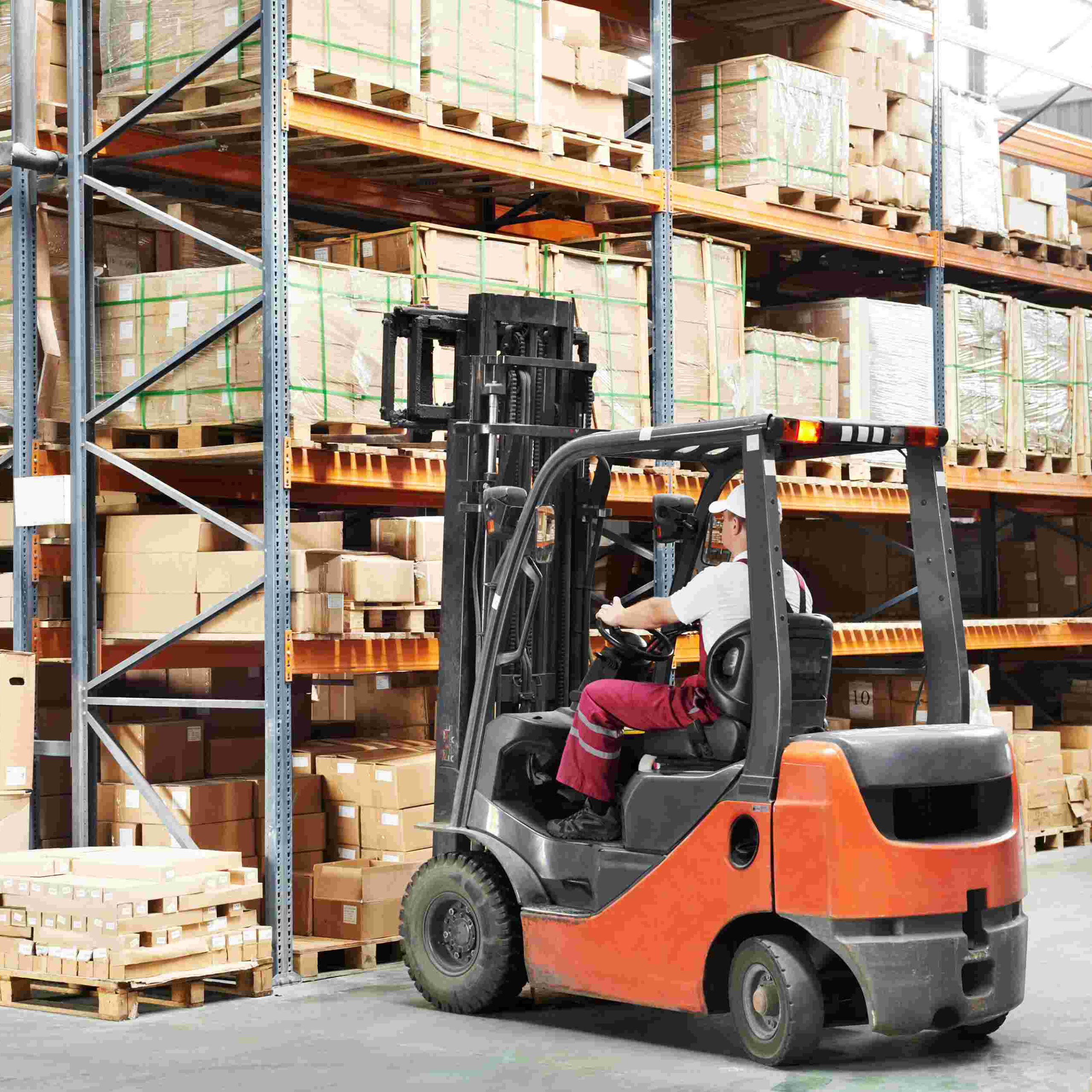 Warehouse worker driver in uniform loading cardboxes by forklift stacker loader